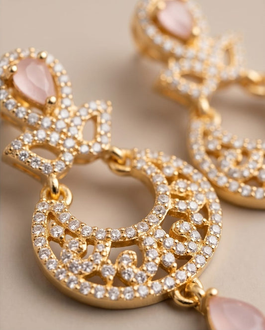 Gold hoop earrings with pink stones on a beige background