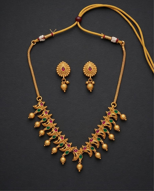 Gold necklace and earrings set on a dark background