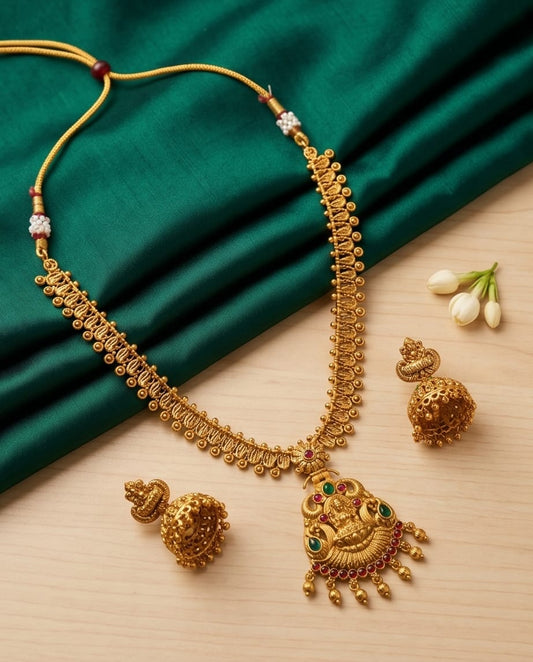 Gold necklace with intricate design on a green fabric background