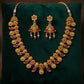 Gold necklace and earrings set on a green cushion