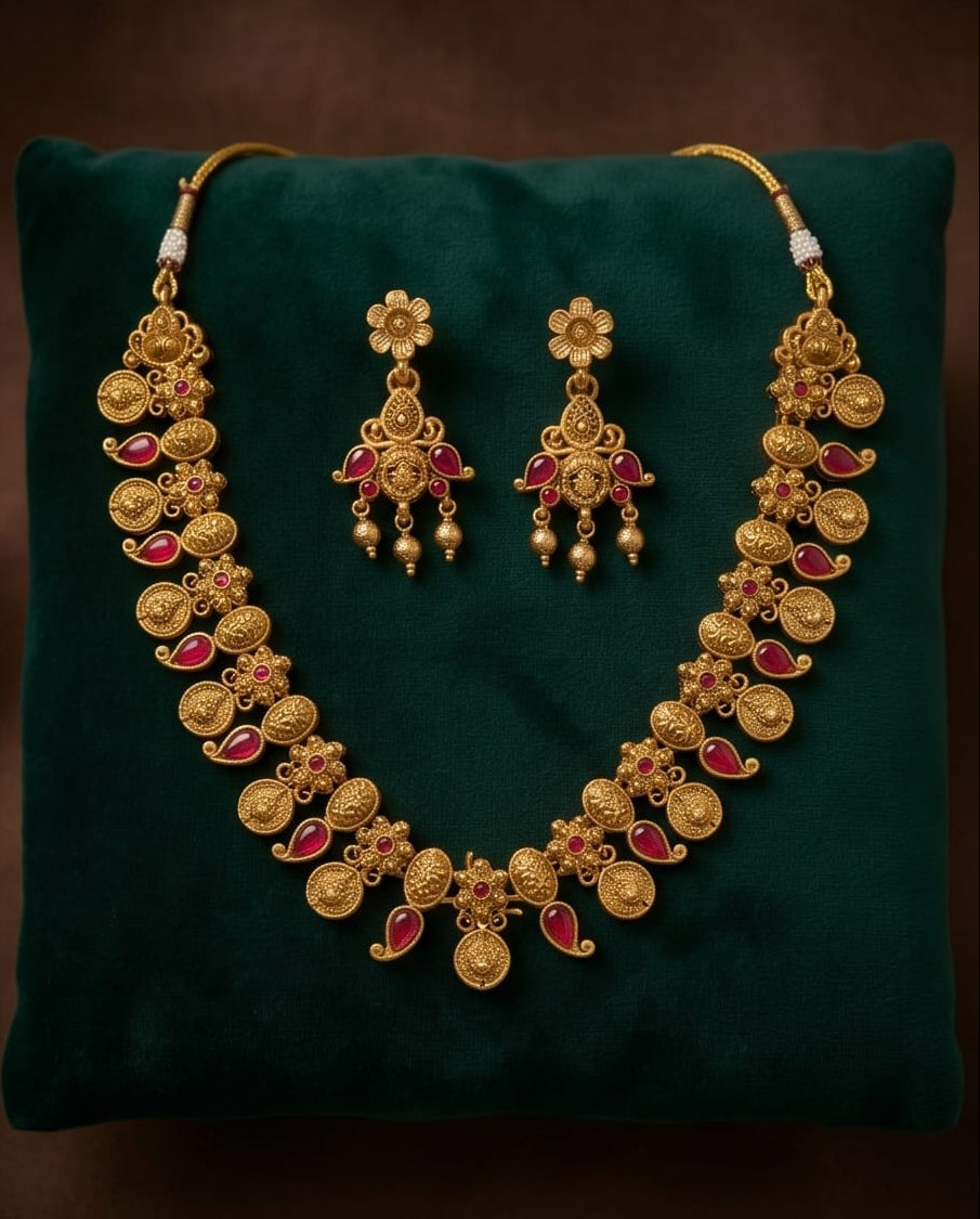 Gold necklace and earrings set on a green cushion