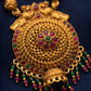 Gold necklace with red and green gemstones on a dark blue background