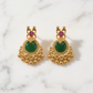 Gold earrings with green gemstones on a marble background