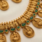 Gold necklace with green gemstones on a light background