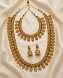 Gold necklace with green stones and matching earrings on a beige fabric background