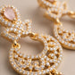 Gold hoop earrings with pink stones on a beige background