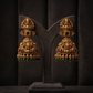 Gold earrings with green and red stones on a dark background