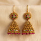Gold earrings with gemstones on a beige fabric background