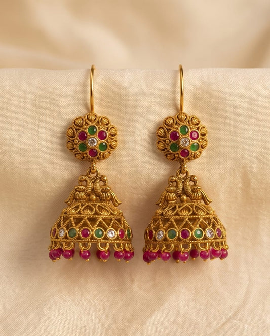 Gold earrings with gemstones on a beige fabric background