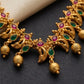 Gold necklace with red and green gemstones on a dark surface