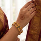 Hand with gold bracelet and henna design, wearing a traditional saree.
