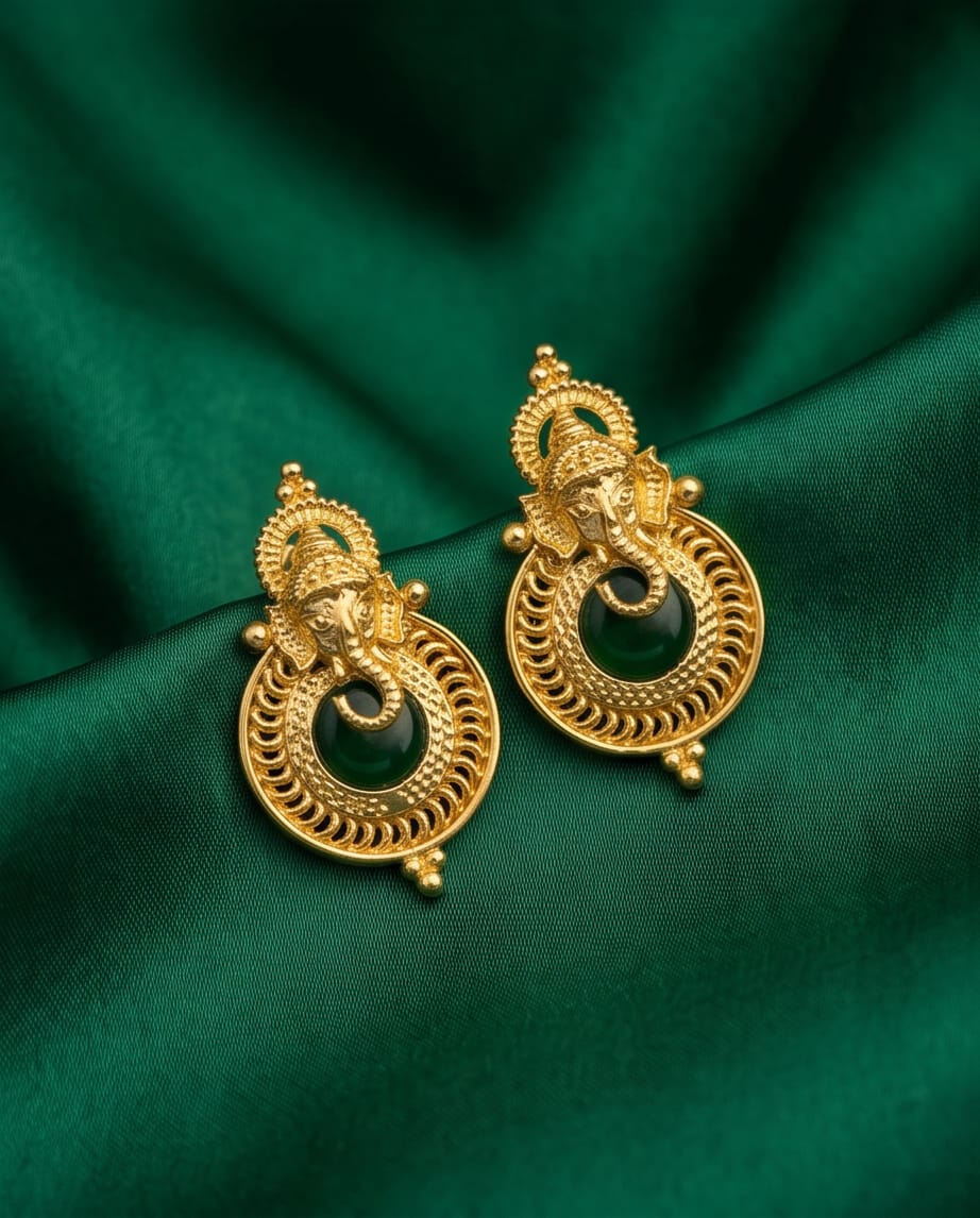 Gold earrings with black stones on a green fabric background