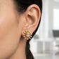 Close-up of an ear wearing a gold and pearl earring with a blurred background