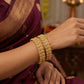 Gold bracelets on a person wearing a purple saree with a blurred background