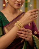 Woman wearing gold jewelry with a blurred background