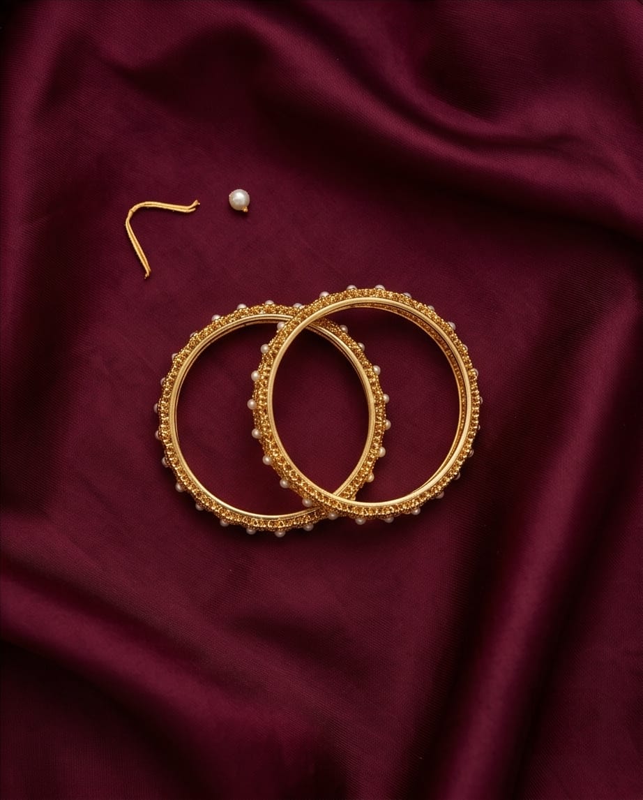 Gold hoop earrings on a maroon fabric background