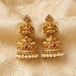 Gold earrings with pearls and red stones on a beige fabric background