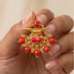 Gold ring with red gemstones held in a hand against a neutral background