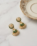 Pair of gold earrings with green and pearl details on a marble surface.