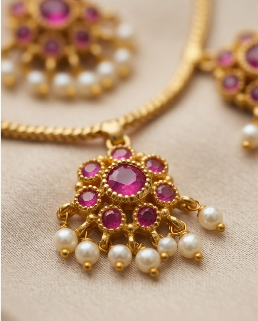 Gold necklace with pink gemstones and pearls on a beige background