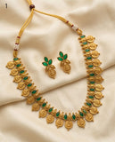Gold necklace with green stones and matching earrings on a beige fabric background
