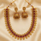 Gold necklace with red stones and matching earrings on a beige fabric background