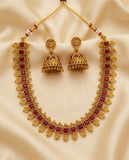 Gold necklace with red stones and matching earrings on a beige fabric background