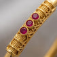 Gold pen with red gemstones on a gray background