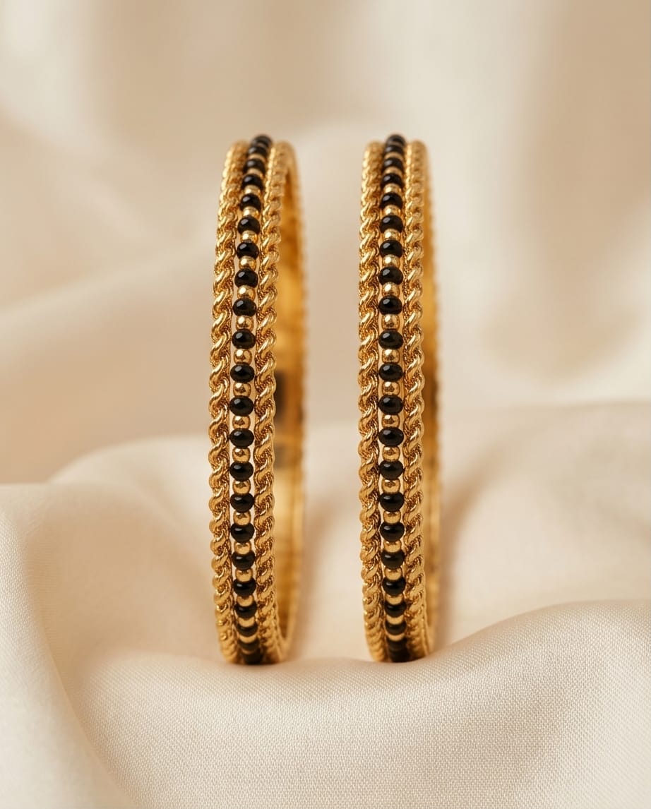 Gold hoop earrings with black beads on a beige fabric background