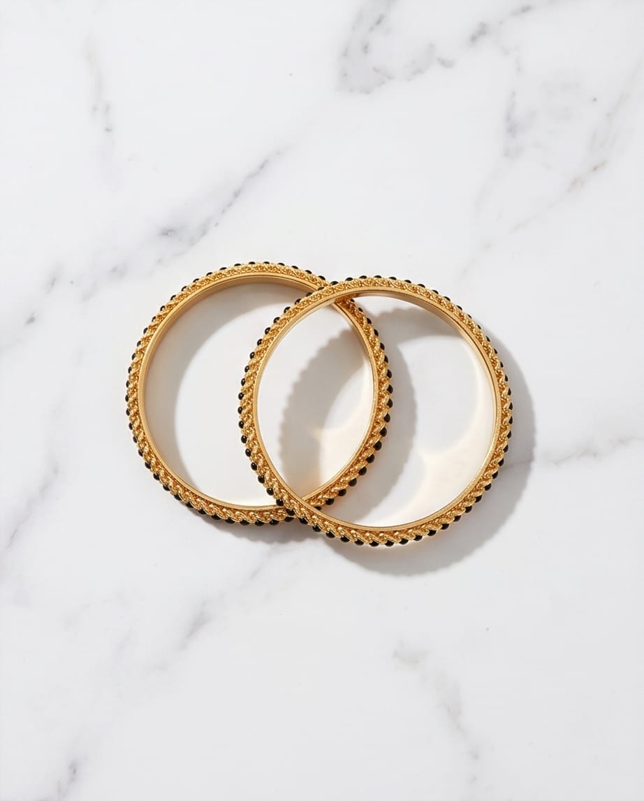 Two gold bangles on a marble surface