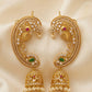 Gold earrings with intricate designs and gemstones on a beige fabric background