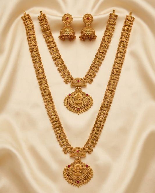 Gold necklace and earrings set on a beige fabric background