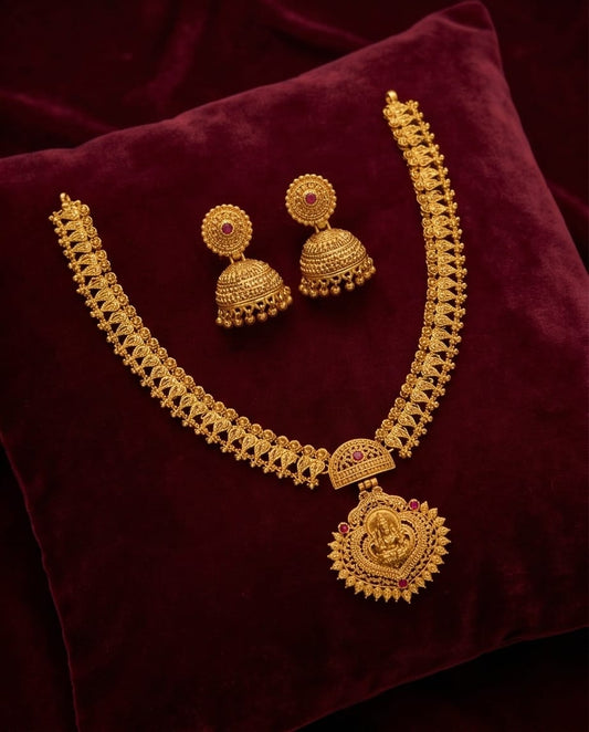 Gold necklace and earrings set on a maroon fabric background