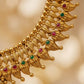 Gold necklace with red and green gemstones on a blurred gold background