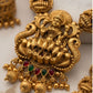 Gold necklace with intricate design and red and green gemstones on a light background