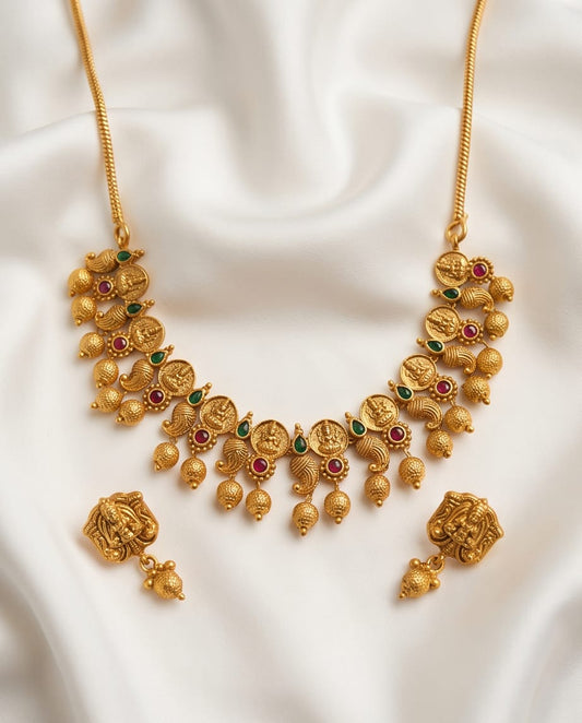 Gold necklace with intricate design on a white fabric background