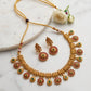 Gold necklace and earrings set on a marble surface with flowers.