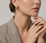 Close-up of a woman wearing gold earrings with a neutral background