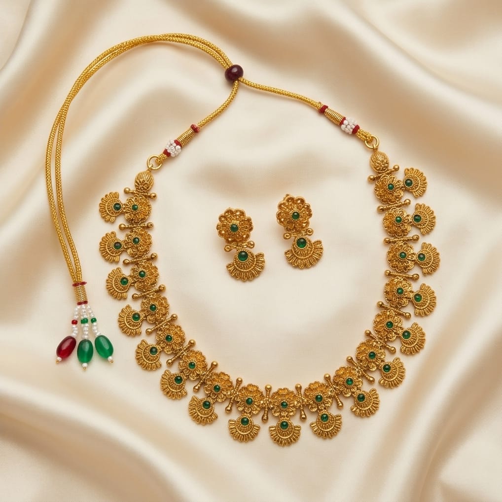 Gold necklace and earrings set on a beige fabric background