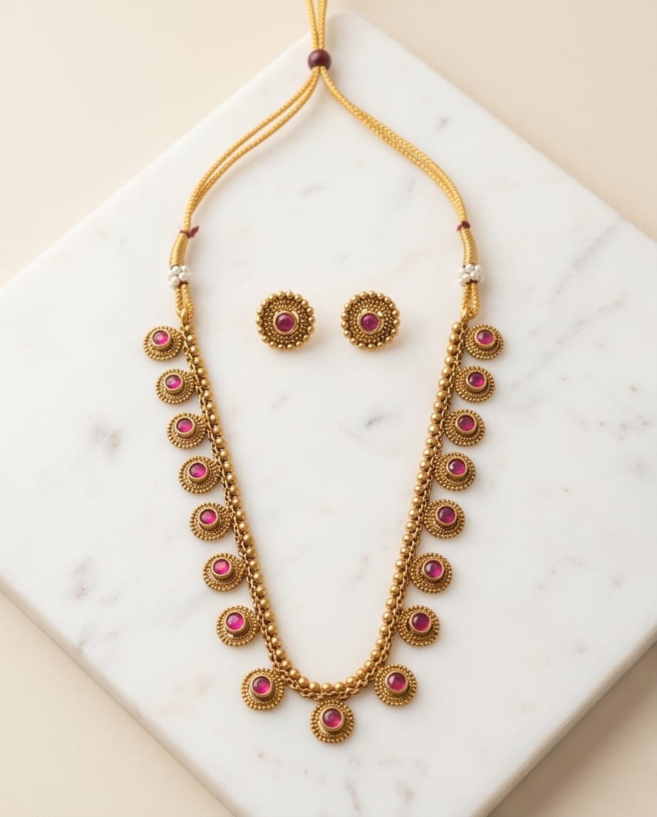 Gold necklace with pink stones on a marble surface
