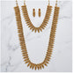 Gold necklace and earrings set on a marble surface